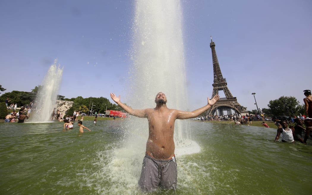 Mężczyzna odpoczywa w fontannach Trocadero naprzeciwko Wieży Eiffla w Paryżu 18 czerwca 2022 r., pośród rekordowo wysokich temperatur panujących we Francji i Europie Zachodniej.