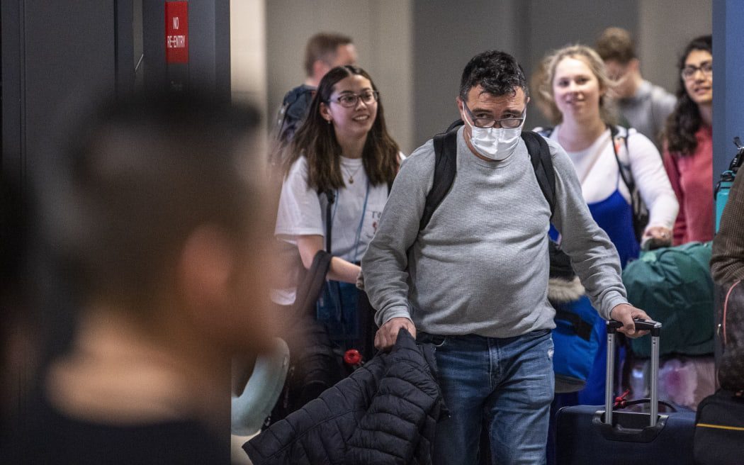 Podróżnik z Brukseli noszący maskę, aby chronić się przed nowym koronawirusem, szuka krewnych w międzynarodowej strefie przylotów na lotnisku Dulles pod Waszyngtonem.