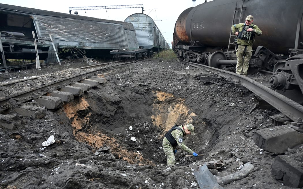 Ekspert medycyny sądowej od materiałów wybuchowych bada krater po wybuchu rakiety na dworcu towarowym w Charkowie, 21 września 2022 r., podczas rosyjskiej inwazji wojskowej na Ukrainę.