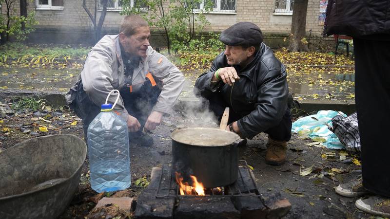 Miejscowi gotują jedzenie na świeżym powietrzu w pobliżu ich domu w Bachmut.